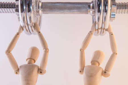 Two puppets pushing a heavy weight with teamworkの写真素材