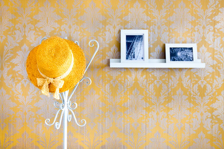 Yellow straw hat on a hat stand and a shelf with black and white pictures