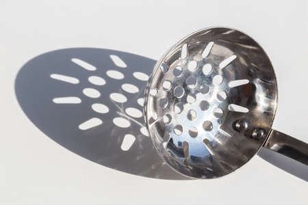 Ladle with holes in the sun throwing a shadowの写真素材