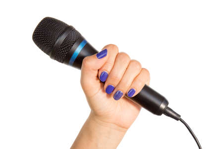 Woman's hand with blue fingernails holding a black microphoneの写真素材