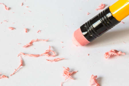 Yellow pencil erasing on white paper with pink crumbsの写真素材