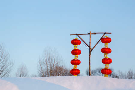 Eight Chinese lanterns on a snow hill hanging from a wooden pillarの写真素材