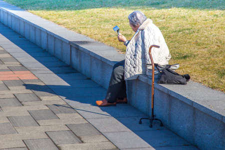 Shanghai,China - 02 10 2016: Old chinese woman with with a cane and an ipad enjoying the sun on a sunny day without pollution in Shanghaiのeditorial素材