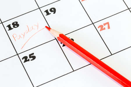 Red pencil on a calendar with the word Payday written on one of the daysの写真素材