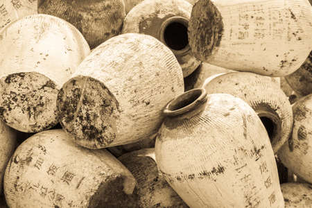 Pile of ancient chinese jugs outside in the sun with the chinese characters for rice wine written on the outsideのeditorial素材