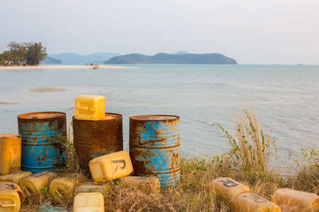Three rusty barrels and plastic canisters next to a a tropical beach in Malaysiaの写真素材