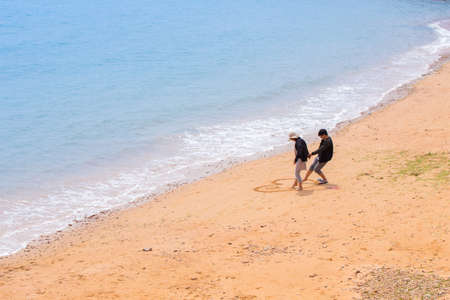Qingdao,China 19/04/2016 Chinese young couple drawing a heart in the sand with their feet at the coast of Qingdao Chinaのeditorial素材