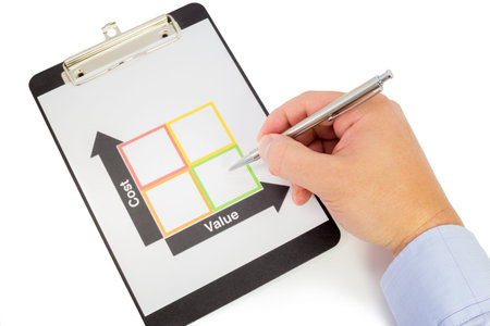 Hand with a pen points at the square with the lowest cost and the highest value in a cost-valueの写真素材