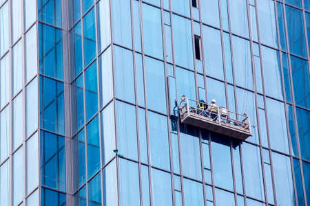 Two Chinese workers inserting windows in a high rise office buildingの写真素材