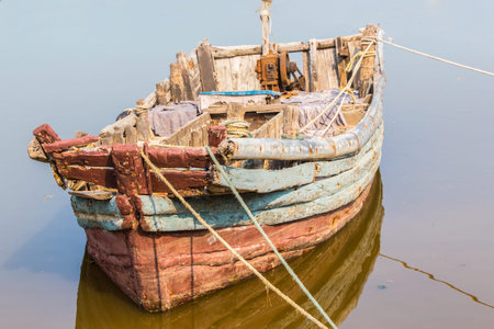 Old Chinese fisherboat on a sunny day with rotten wood and a rusty engineの写真素材