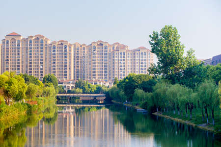 Shanghai,China 07/22/2016 Residential high rise buildings in a park like area with a river and a bridge reflecting the scenery in Shanghaiのeditorial素材