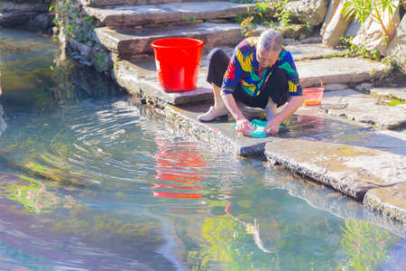 Likeng,China Old woman is washing clothes beside of the river.のeditorial素材