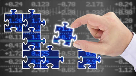 Hand putting pieces of a puzzle together revealing a blue glowing stock wall financial business success conceptの写真素材