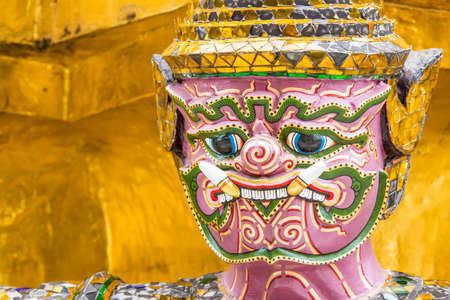 Bangkok,Thailand 05/09/2016 Close up of crafted statue with a fierce facial expression in front of a golden temple in Thailandのeditorial素材