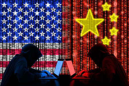 American hacker sitting opposite of a chinese hacker cyberwar concept in front of binary flagsの写真素材