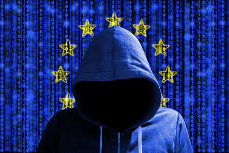 Hacker in a dark red hoody in front of a digital european flag and binary streams background cybersecurity conceptの写真素材