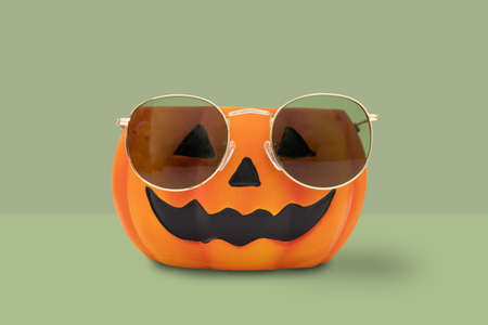 Halloween pumpkin with glasses on green background. Halloween minimal idea concept.の写真素材