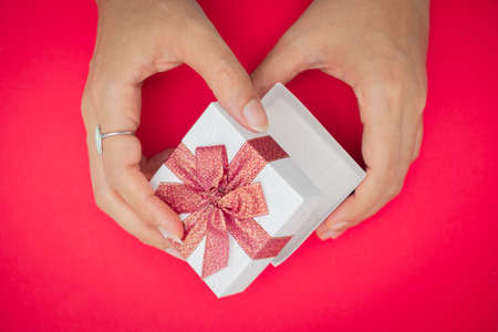 Hand holding white gift box, Used for New Year's Eve, Christmas, Birthday, Valentine's Day. Isolated on redbackgroundの写真素材