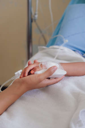 Mother holding child's hand who fever patients in hospital to give encouragement.の写真素材