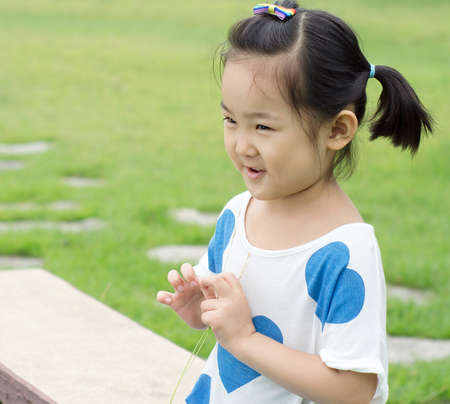 Happy little girl sitting on a park bench.の写真素材