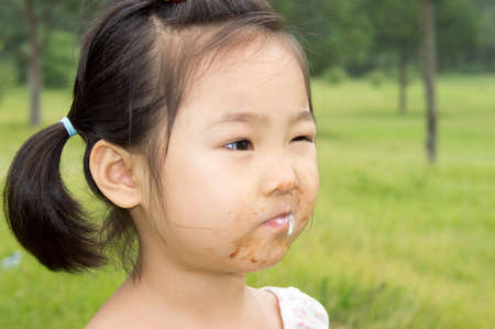 beautiful Asian little girl eating an ice cream and about to take a great big biteの写真素材