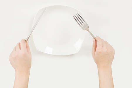 Close-up hand and cutlery isolated in the white backgroundの写真素材