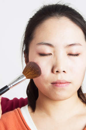 Asian woman having blush applied by a beauticianの写真素材