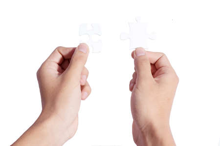 Two hands holding puzzle pieces and connecting themの写真素材