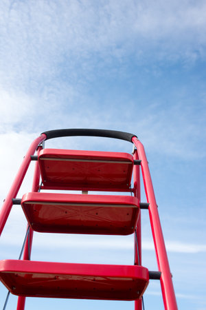 In the blue sky white clouds feature in the background of the ladderの写真素材