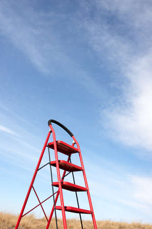 In the blue sky white clouds feature in the background of the ladderの写真素材