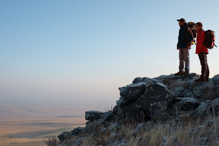Two hikers enjoying sunrise from top of a mountain