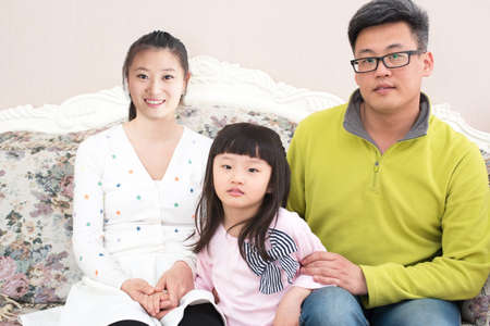 Father and mother and daughter sitting on the sofa family photo.の写真素材