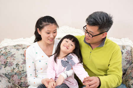Father and mother and daughter sitting on the sofa family photo.の写真素材