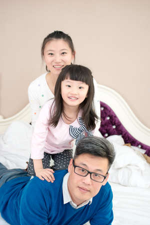 Happy family looking at the camera on their bedの写真素材