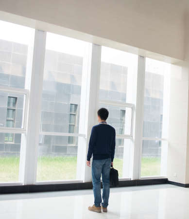 Business men think about standing in office lobbyの写真素材