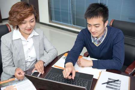 Image of two young businessmen using laptop at meetingの写真素材