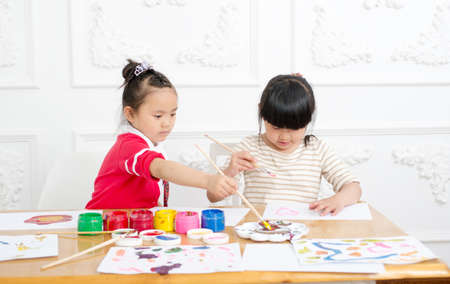 Two preschool girls are seriously painting. Indoorsの写真素材