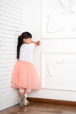 sad little girl standing near the wallの写真素材