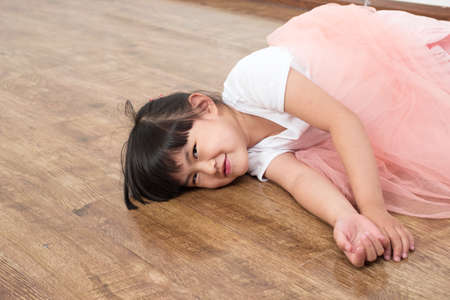Happy smiling little girl lying on a wooden floorの写真素材