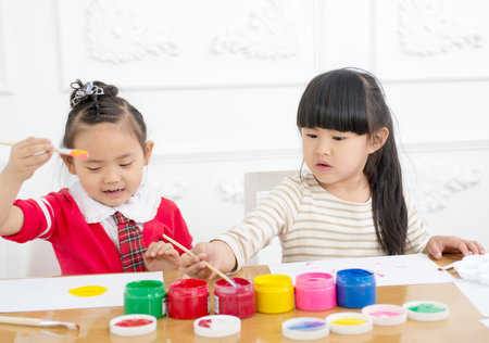 Two preschool girls are seriously painting. Indoorsの写真素材