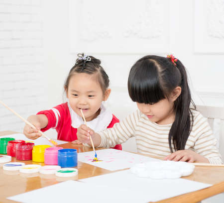 Two preschool girls are seriously painting. Indoorsの写真素材