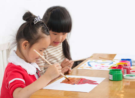 Two preschool girls are seriously painting. Indoorsの写真素材