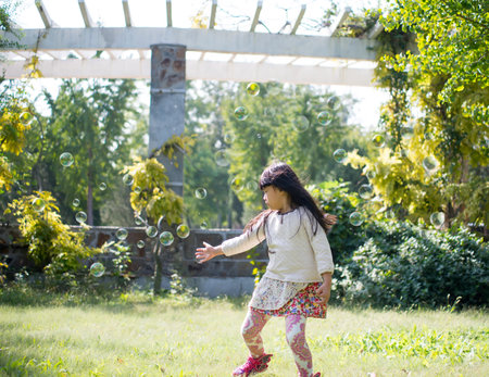 Portrait of a little girl blowing soap bubbles at the parkの写真素材