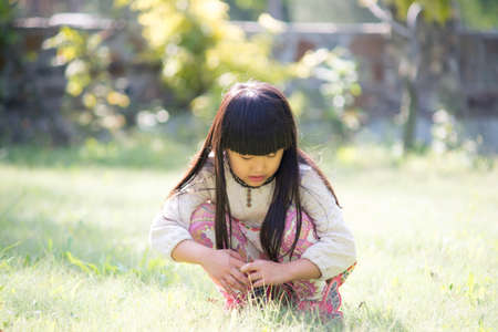 The little girl to play on the lawn. Looking for flowersの写真素材