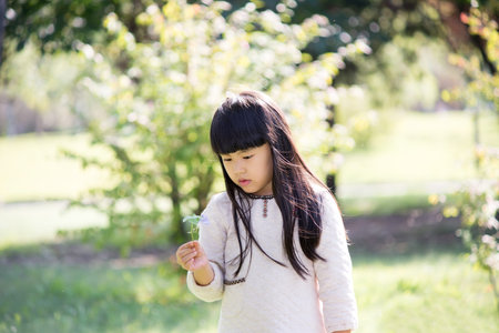 The little girl likes flowers. On the lawn next to the park to play.