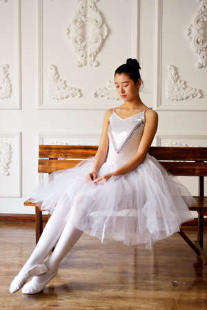 Beautiful female ballet dancer sitting on a benchの写真素材