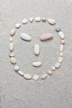 Pebble smiling isolated on a sand backgroundの写真素材