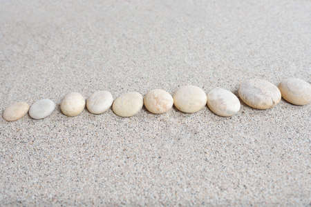 Few stones arranged on beach sand with a bright backgroundの写真素材