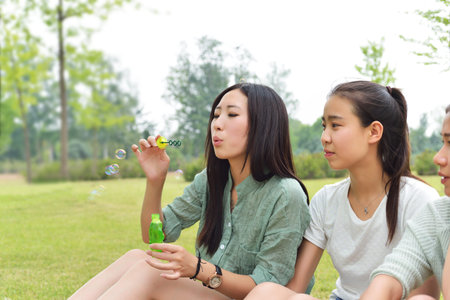 Two ladies sitting on the lawn playing with bubblesの写真素材