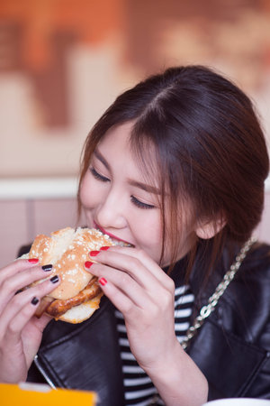 Charming Chinese girl eating hamburger.